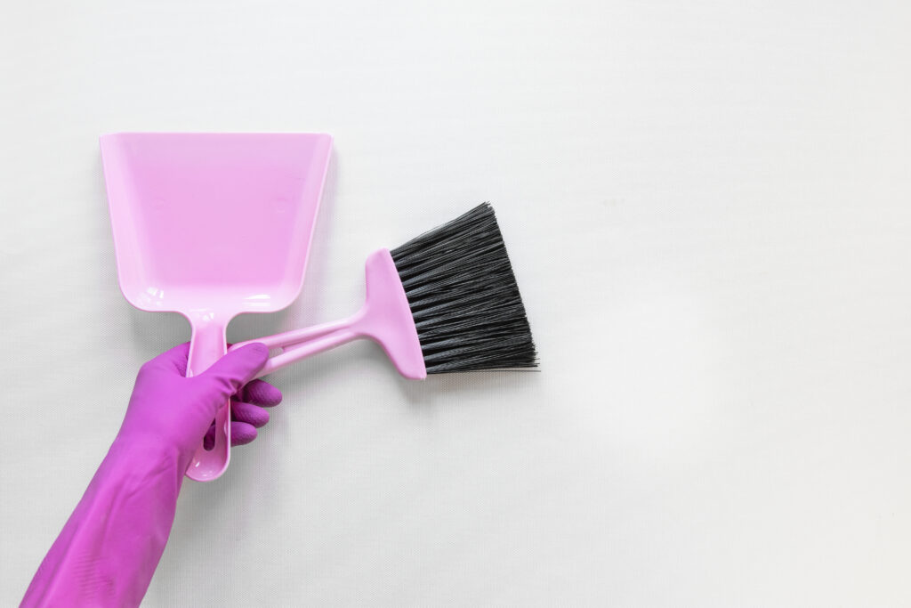 close up person with purple gloves holding small broom